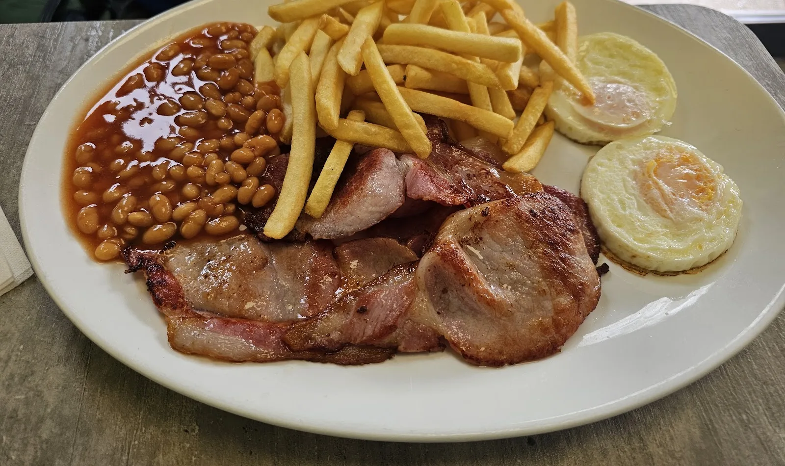 Bacon, eggs, chips and beans on a white plate